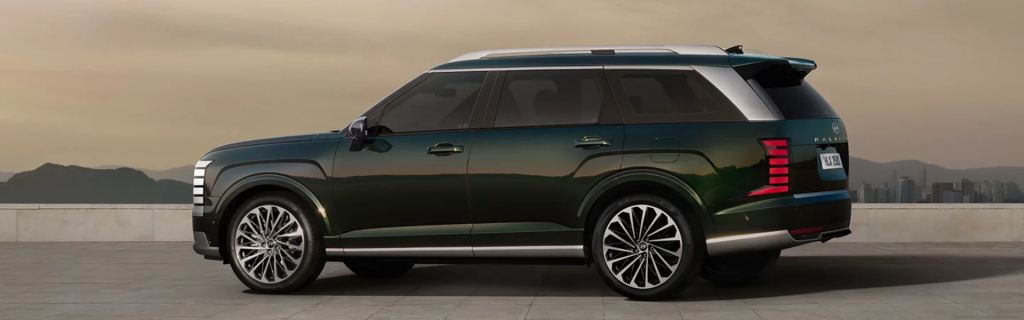 A side view of a green and silver 2026 Hyundai Palisade SUV against a scenic background.