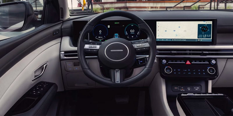 Interior view of a Hyundai car, showcasing the steering wheel and dashboard with digital displays and controls.