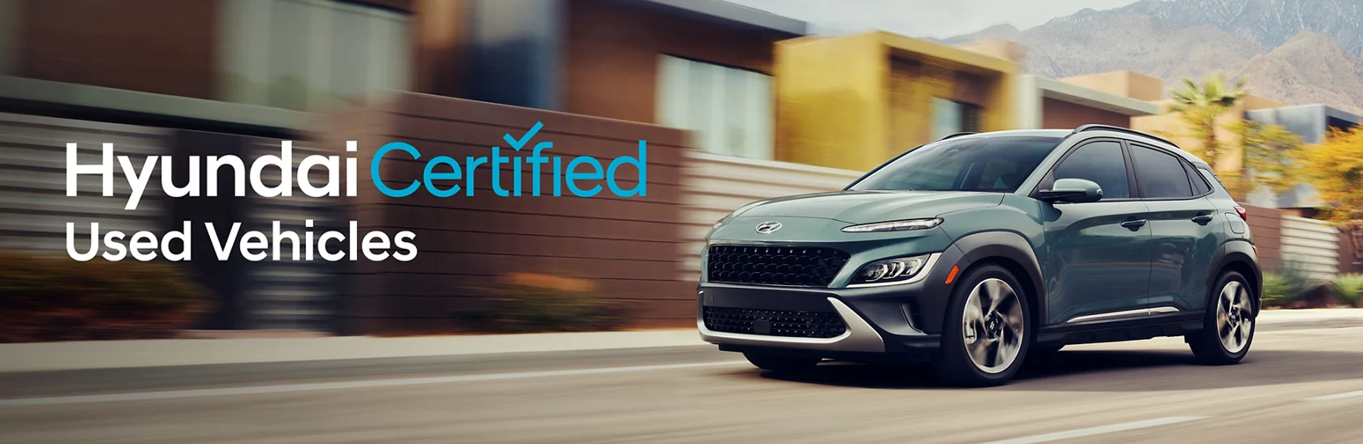 A Hyundai vehicle driving on a street with buildings in the background, alongside the text "Hyundai Certified Used Vehicles."