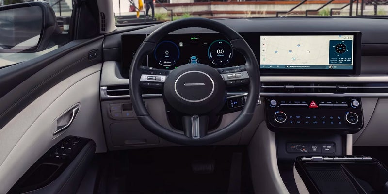 The interior of a Hyundai car featuring a digital dashboard, steering wheel, and multiple screens displaying various driving metrics and navigation.